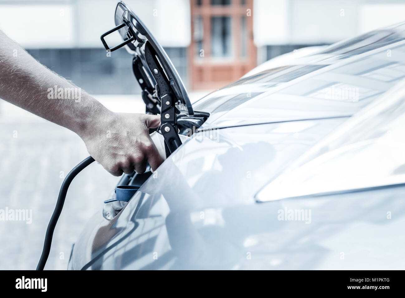 Close up of male hand holding electric car charging nozzle Stock Photo