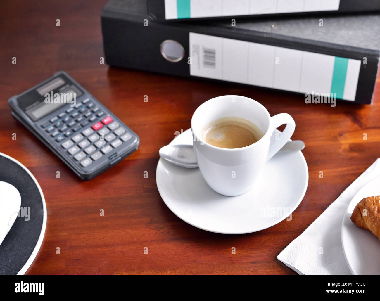 Workplace scene with breakfast. Breakfast background on a working place, croissant and coffee cup. Computer, snack and hot drink, office scene, break. Stock Photo