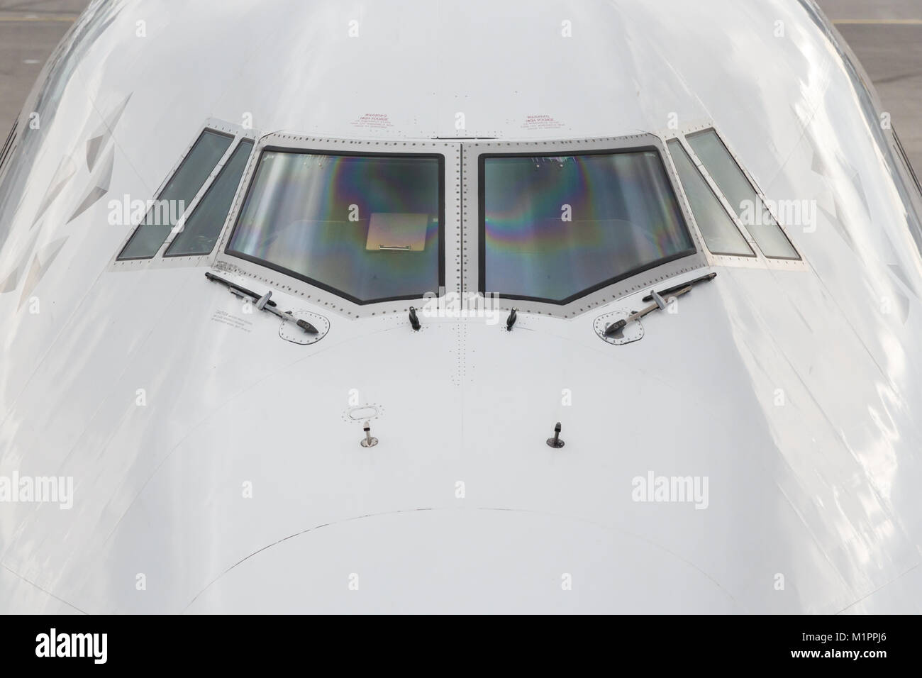 Close up of the front windshield and wipers of a jumbo jet with the airport as a  background. Stock Photo