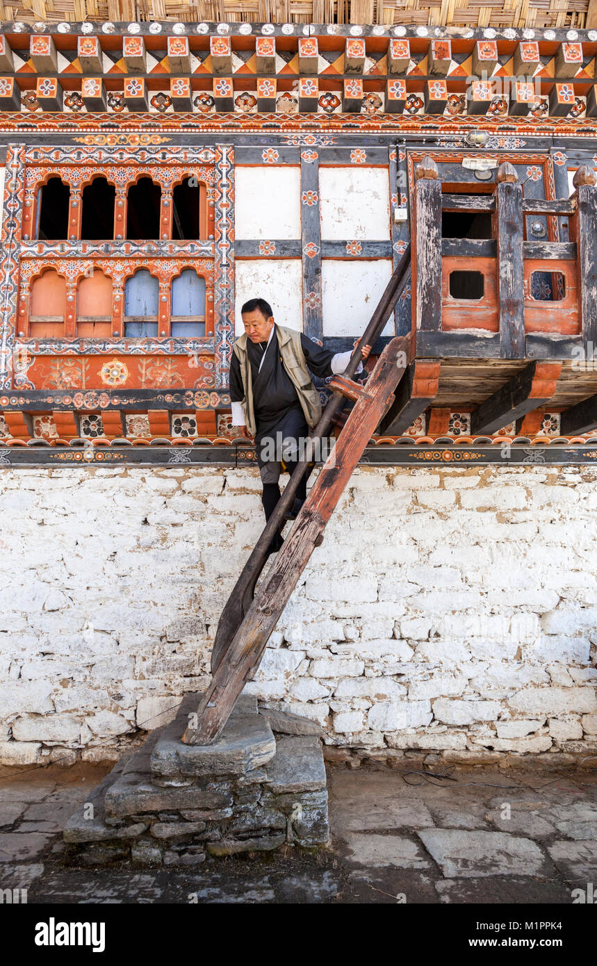 Bumthang, Bhutan.  Man Descending Stairs in the Prakhar Dzong, Wearing Traditional Gho. Stock Photo