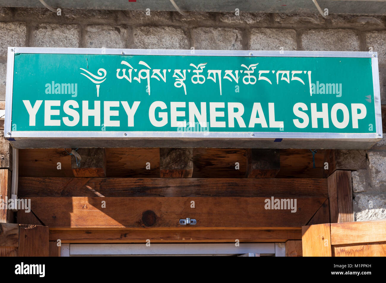 Bumthang, Bhutan.  Dzongkha (Tibetan) Alphabet on Bilingual Sign, Jakar Shop. Stock Photo