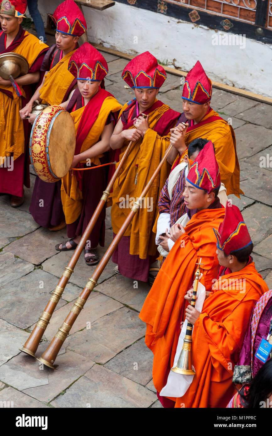 Bumthang, Bhutan.  Buddhist Monks in Religious Ceremony in Courtyard of  Jambay Lhakhang Monastery.  Two are holding Dung-chens, the Tibetan Trumpet. Stock Photo