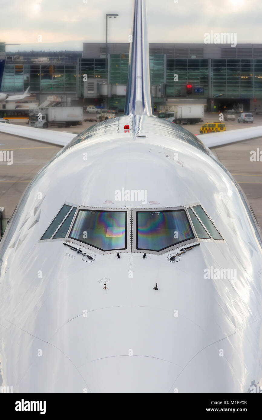 High angle close up of the front windshield and wipers of the jumbo jet nose with the airport as a  background. Stock Photo
