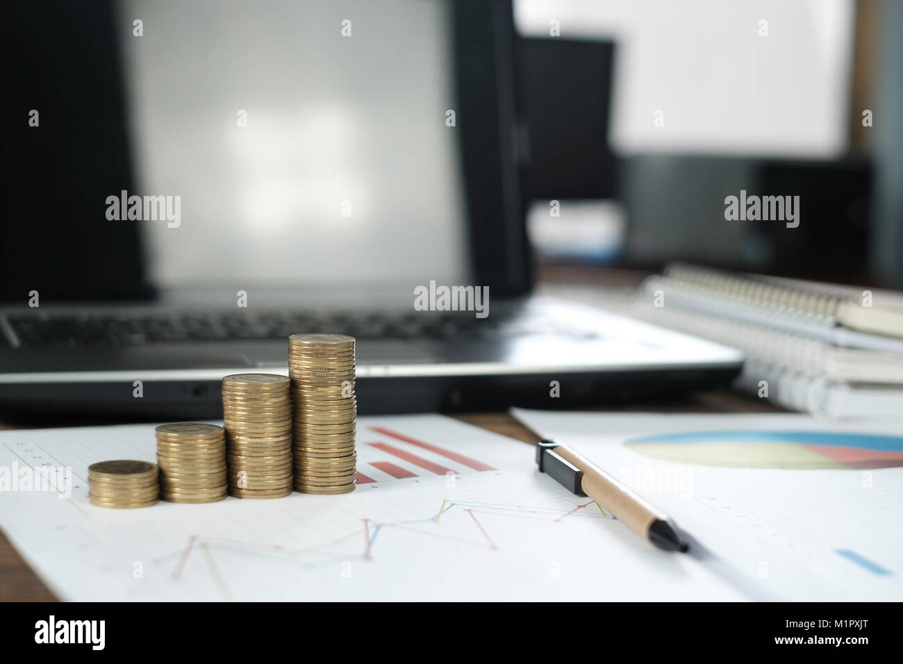 Step of coins stacks with notebook laptop computer and financial graph ...