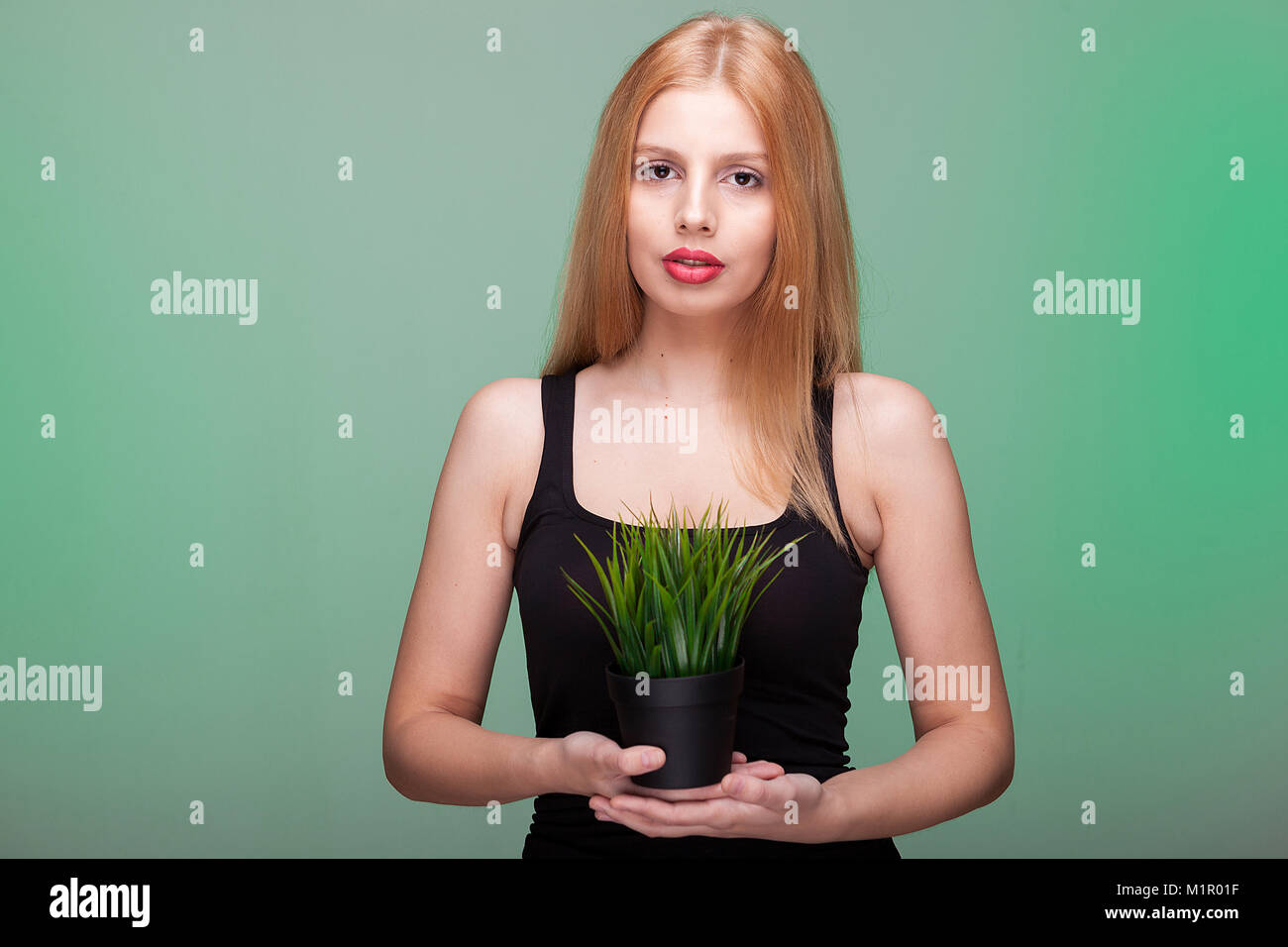 Woman looking at camera and holding a plant in pot Stock Photo - Alamy