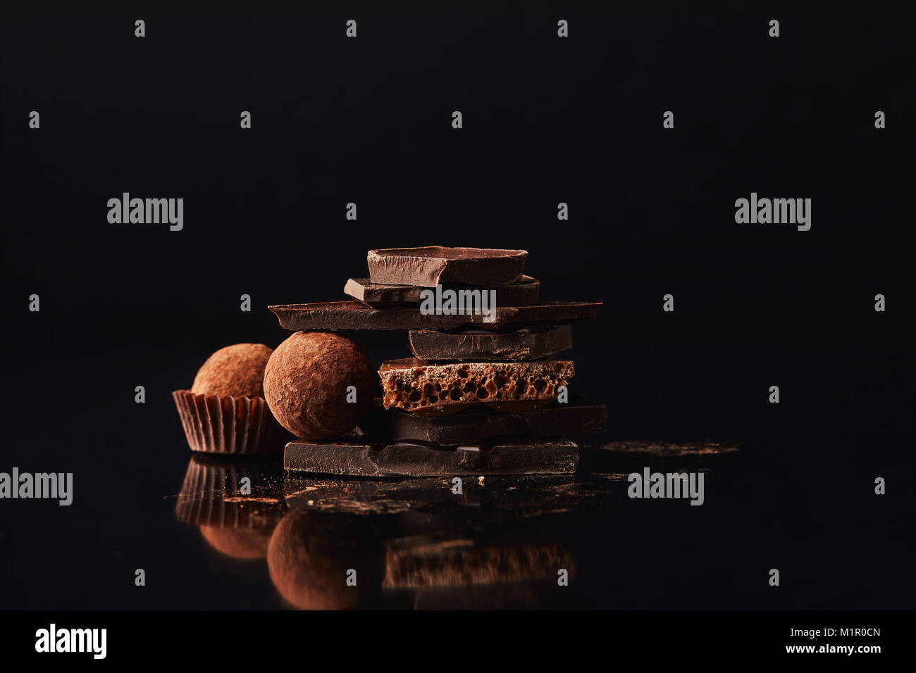 close up view of arrangement of truffles and chocolate bars on black Stock Photo