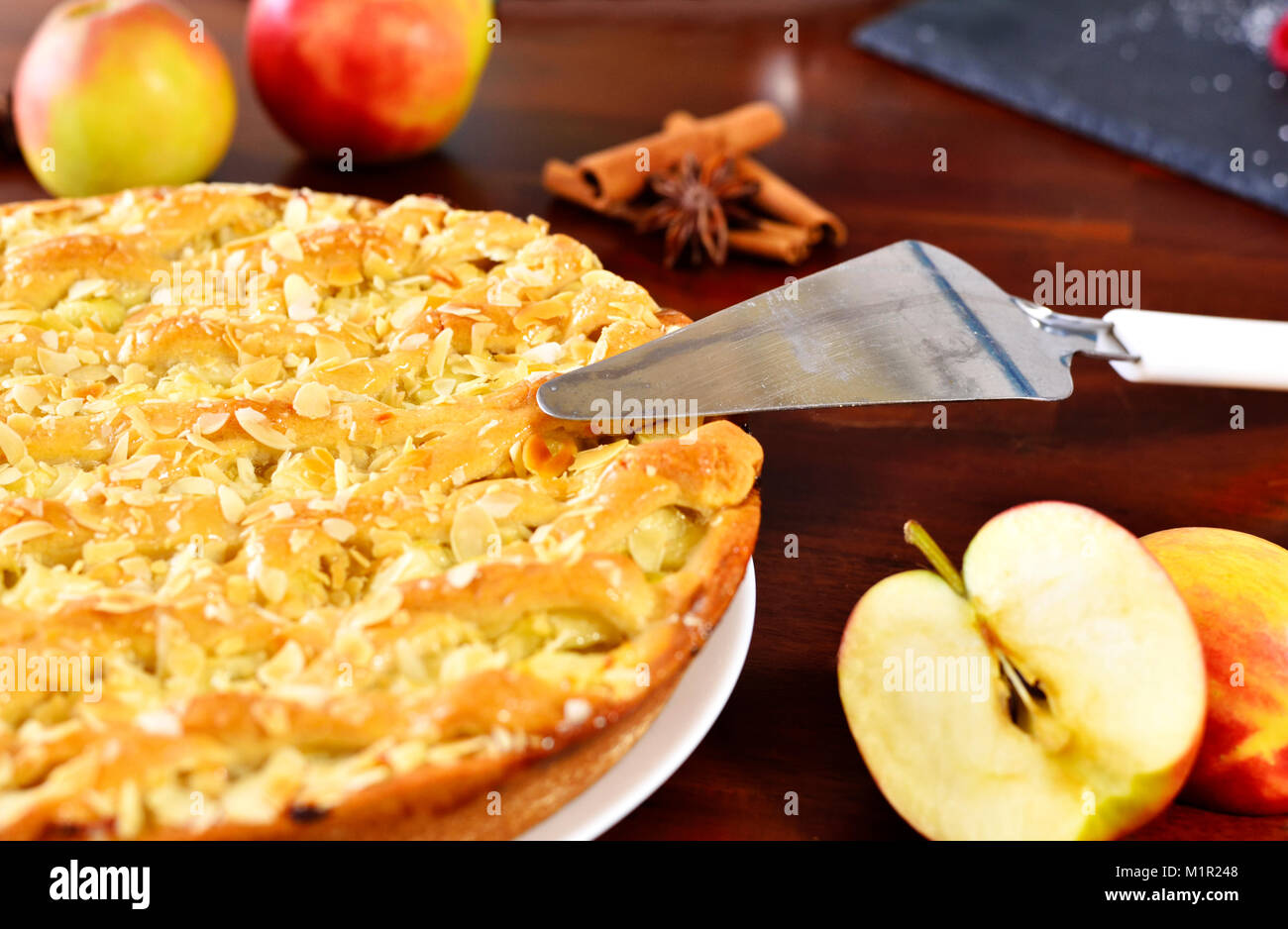 Fresh apple pie or fruitcake on a wooden table. Apple pie and fresh apples, cinnamon and star anise. Cake background. Stock Photo
