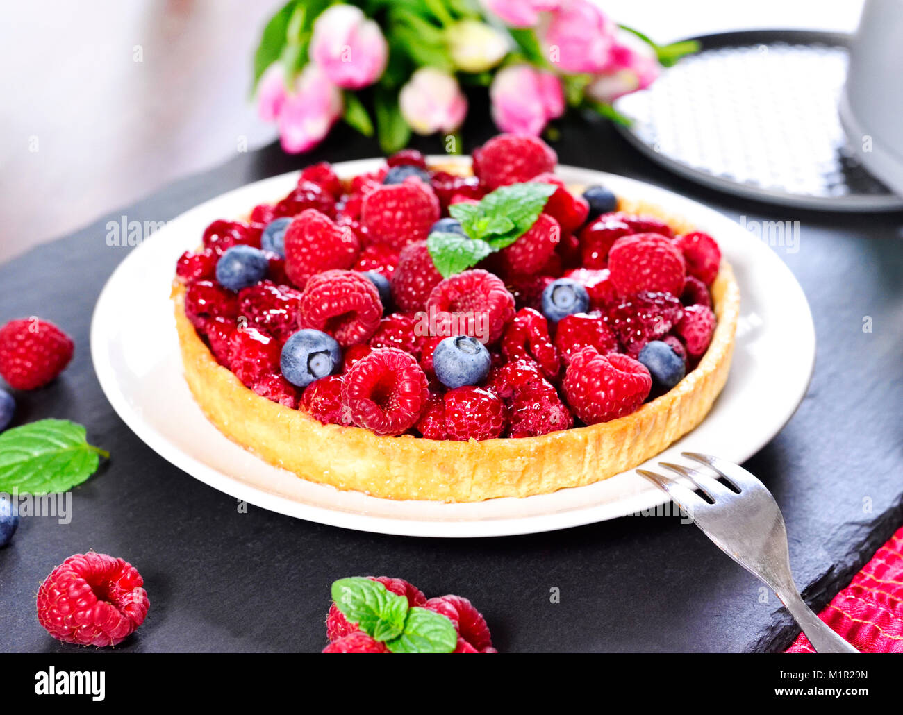 Beautiful fruit cake. fresh birthday cake with raspberries and blueberries, biscuit pie and birthday decoration. Fruitcake, summer tart on a table. Stock Photo
