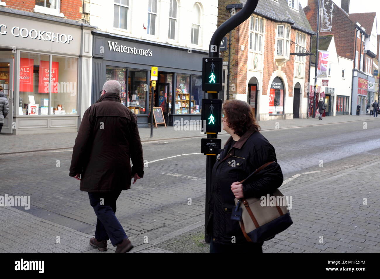 An older woman looks at a man crossing a deserted street at a pedestrian crossing in Brentwood Essex UK. Stock Photo