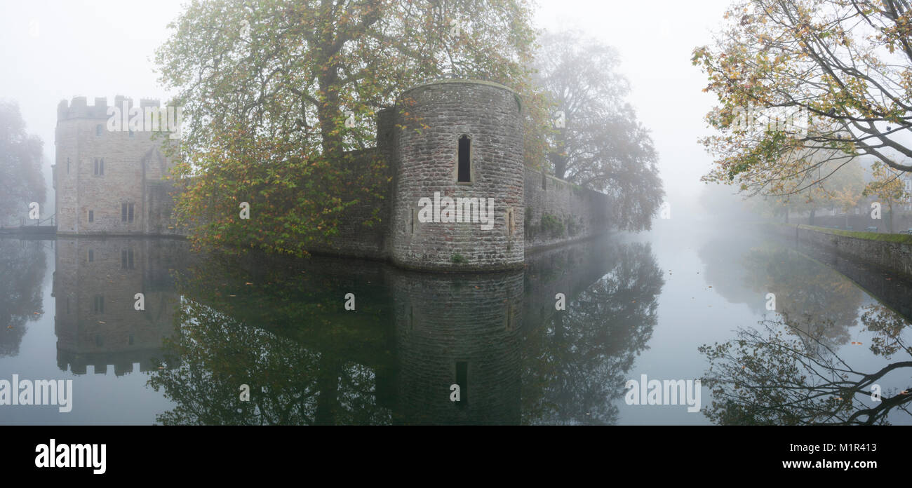 A panoramic view of the Bishop's Palace and moat shrouded in thick fog on an autumn morning in early November, Wells, Somerset, England. Stock Photo