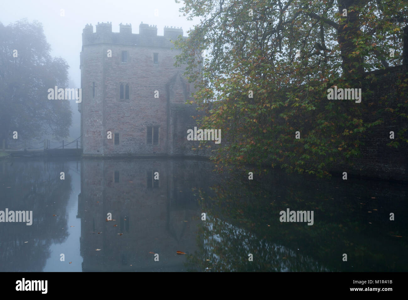 The Medieval gatehouse to the Bishop's Palace reflected in the moat and shrouded in thick mist on a November morning, Wells, Somerset, England. Stock Photo