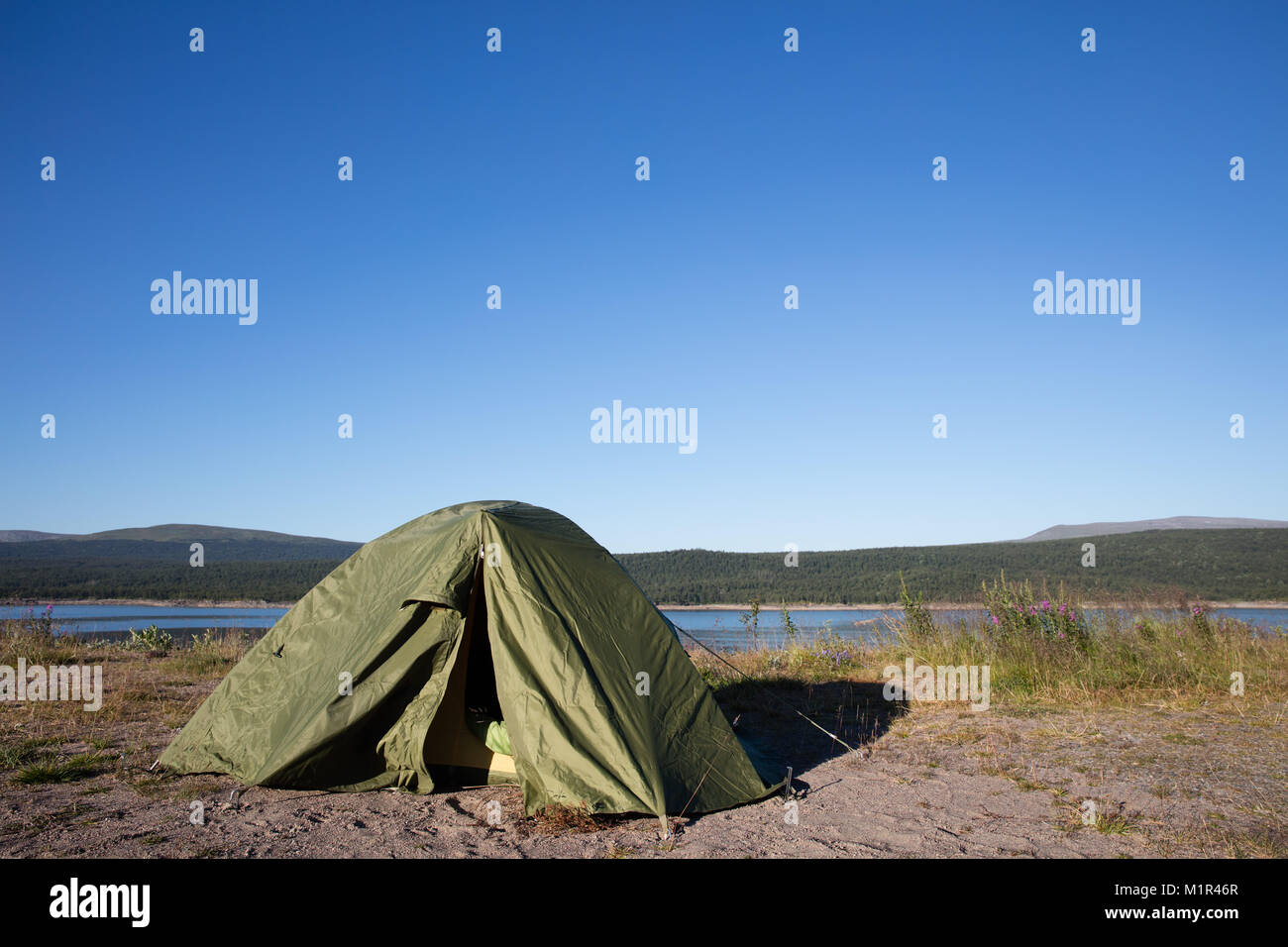 Tent in swedish wilderness during midsummer, camping near the river, moon in the background Stock Photo