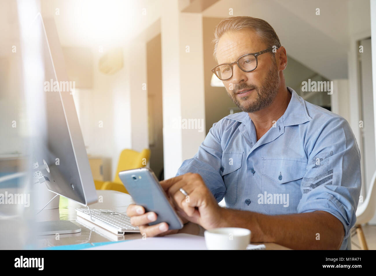 Worker Using Smartphone Home-office worker using smartphone Stock Photo - Alamy
