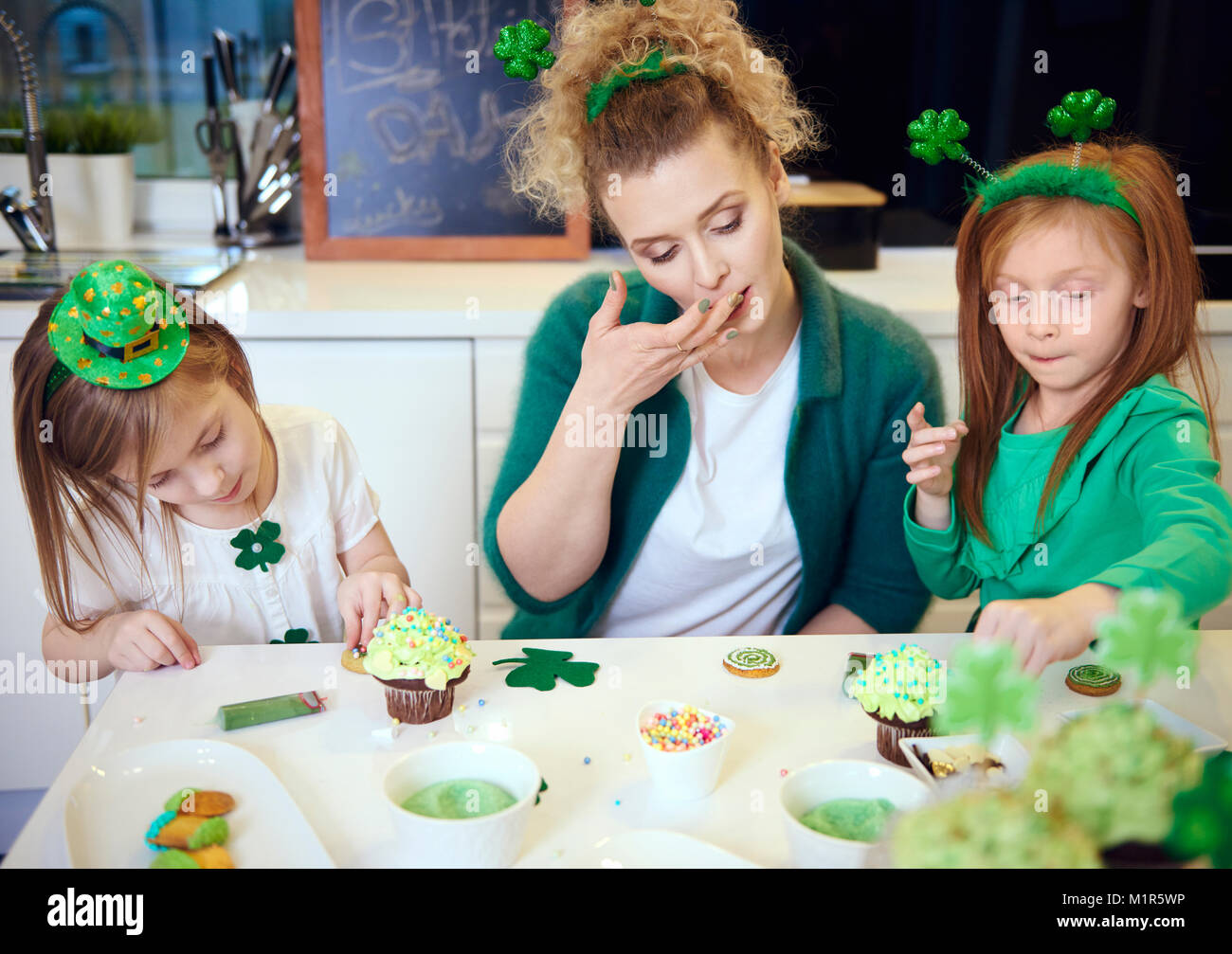 Mother with children decorating cupcakes at kitchen Stock Photo