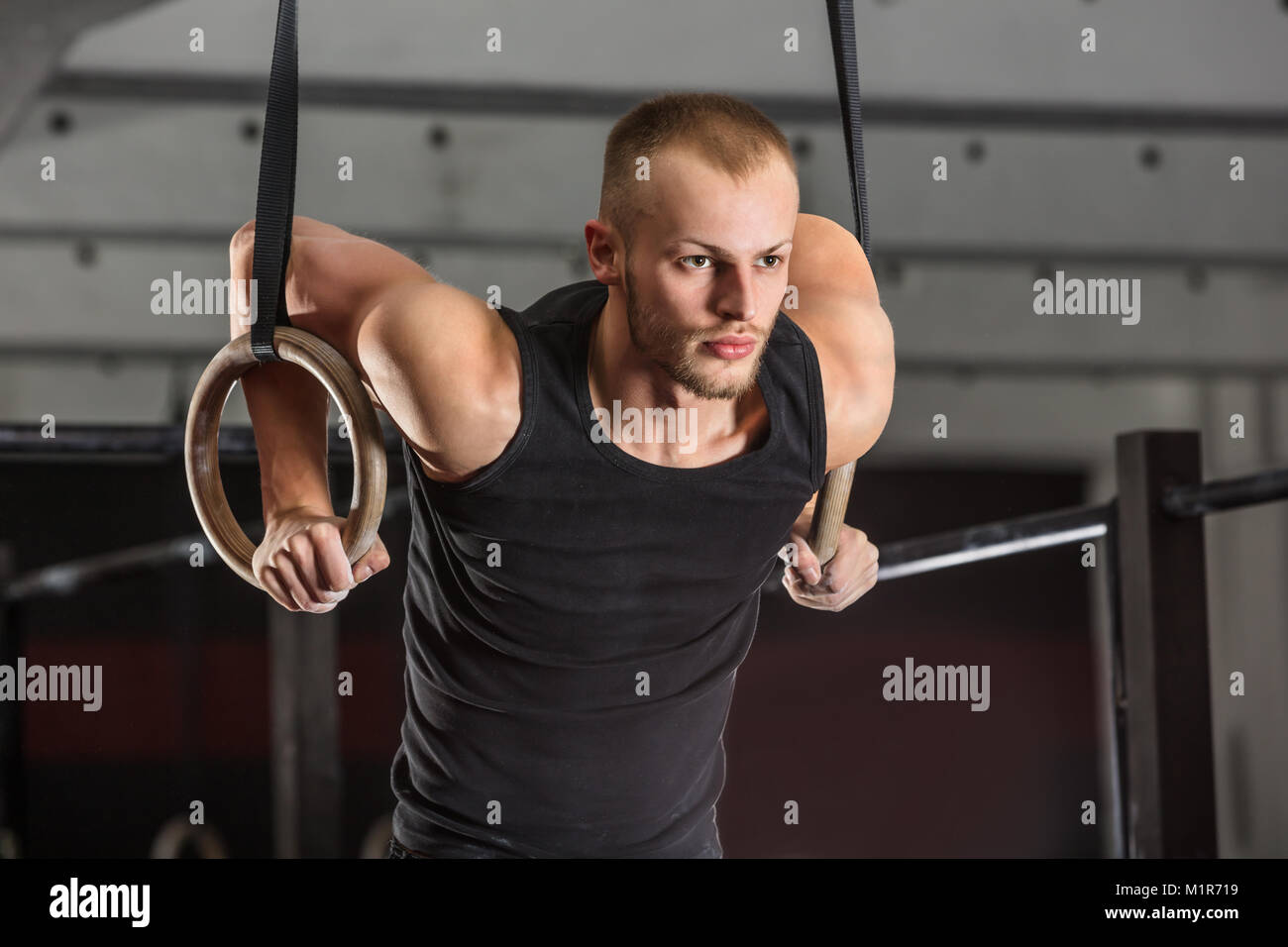 Portrait Of A Fitness Man Training Arms With Gymnastics Rings In The Gym Stock Photo