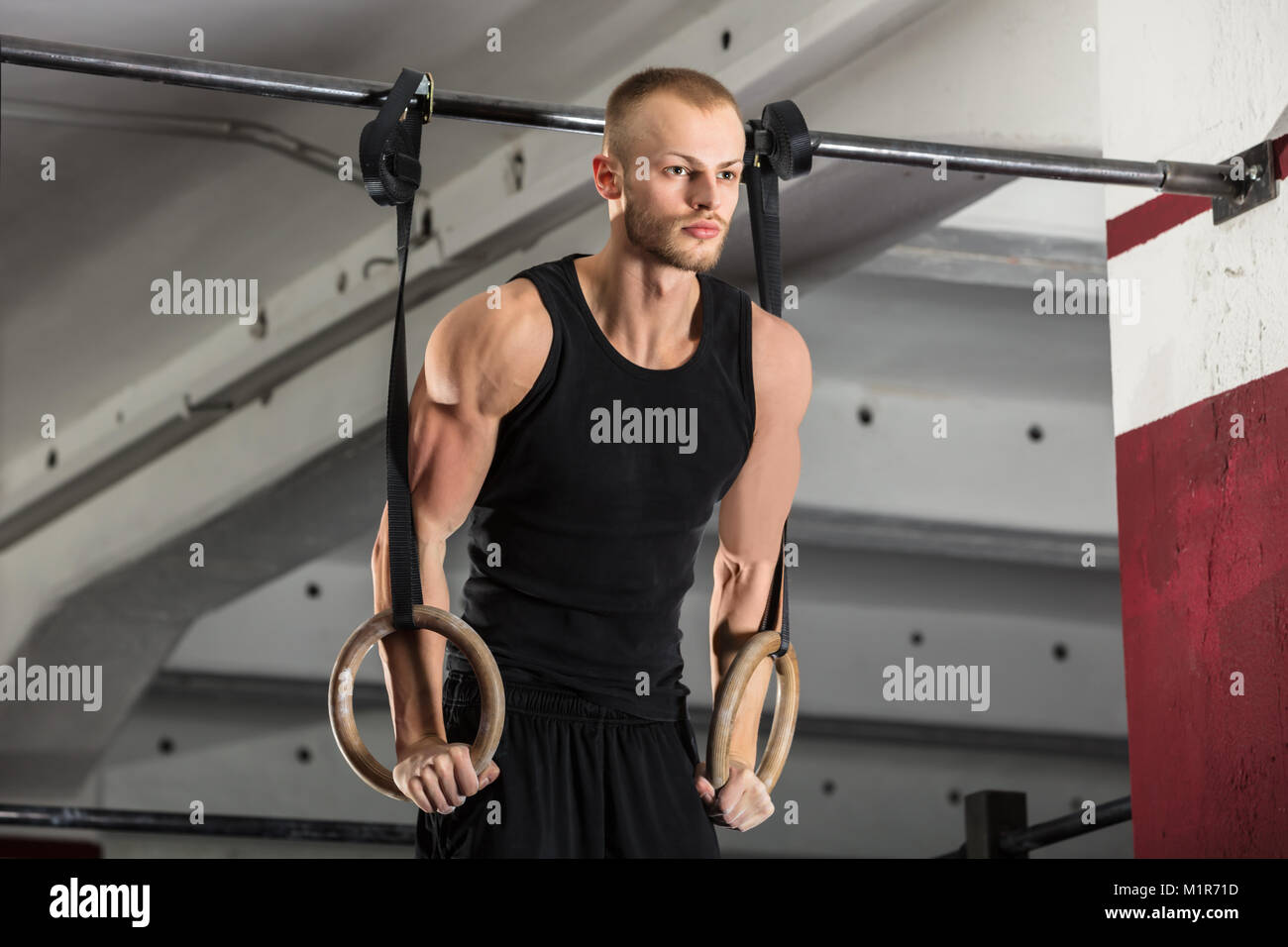 Portrait Of A Fitness Man Training Arms With Gymnastics Rings In The Gym Stock Photo