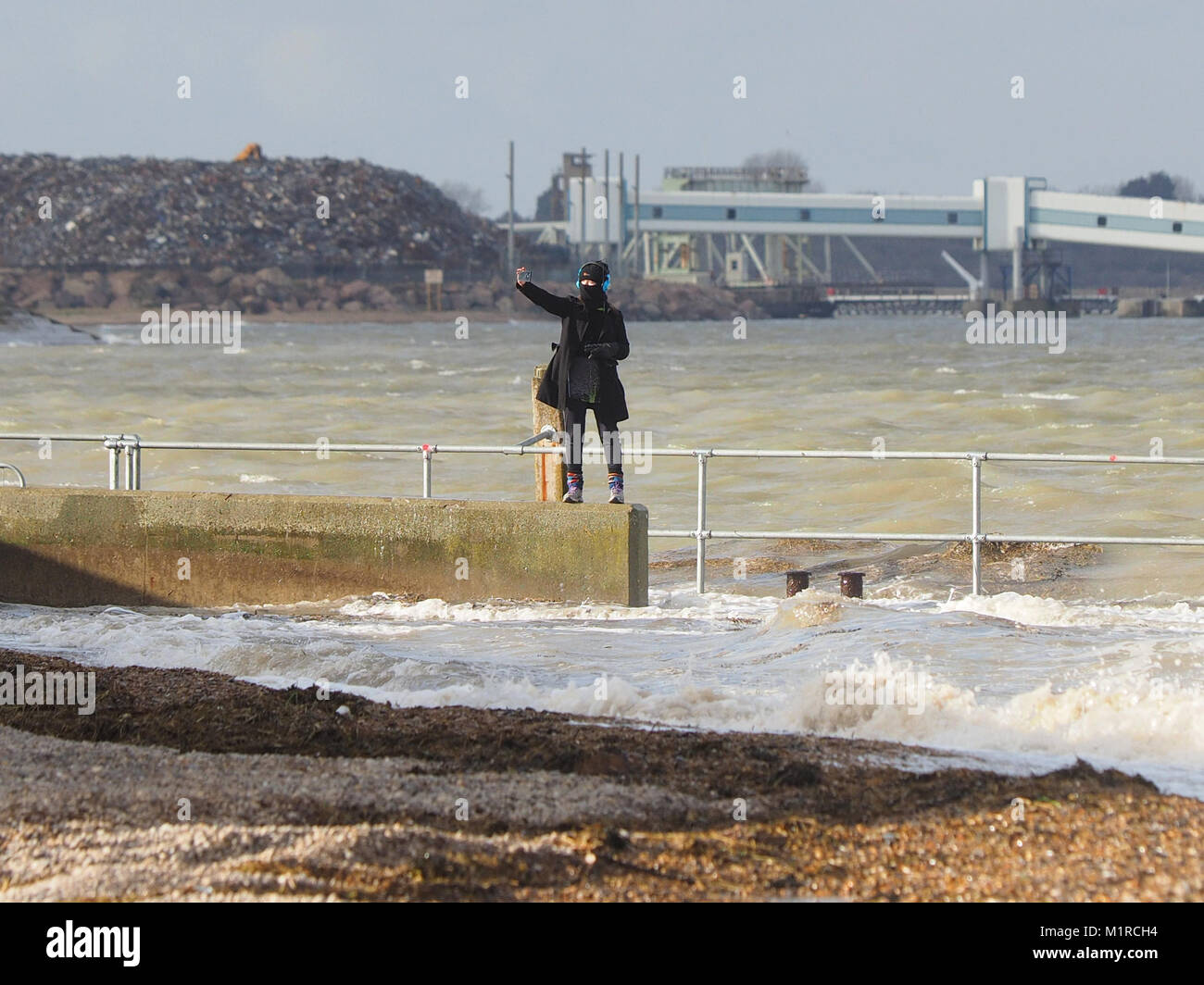 Sheerness, Kent, UK. 1st Feb, 2018. UK Weather: a young woman takes a surge tide selfie as the Neptune Jetty is covered by water during today's surge tide. Sunny spells but with a strong and cold westerly wind. Credit: James Bell/Alamy Live News Stock Photo