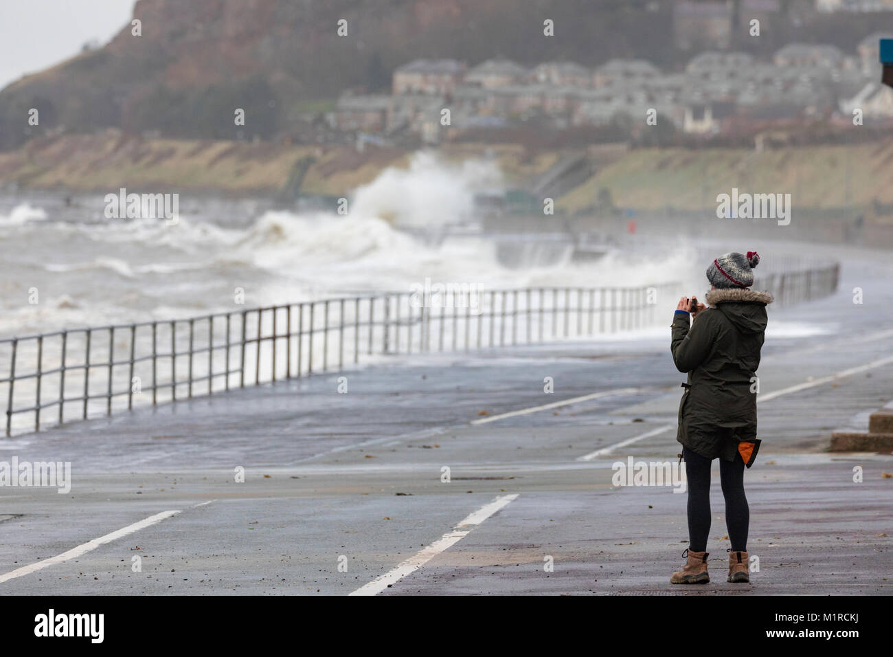 Colwyn Bay, Conwy County, Wales, UK 1st February 2018, UK Weather: Cold weather with high tide and windy weather have provided ideal conditions for Natural Resources Wales to provide flood warnings for the North Wales Coast including Colwyn Bay. A person taking a photograph of the hugh waves along the promenade at Colwyn Bay as huge waves batter the coastal resort with flood warnings in place, Conwy County, Wales Â© DGDImages/Alamy Live News Stock Photo