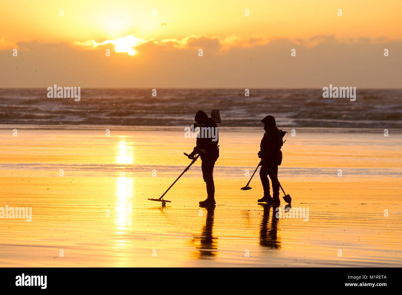 Two metal detectorists with a shovel and a spade scour Blackpool beach