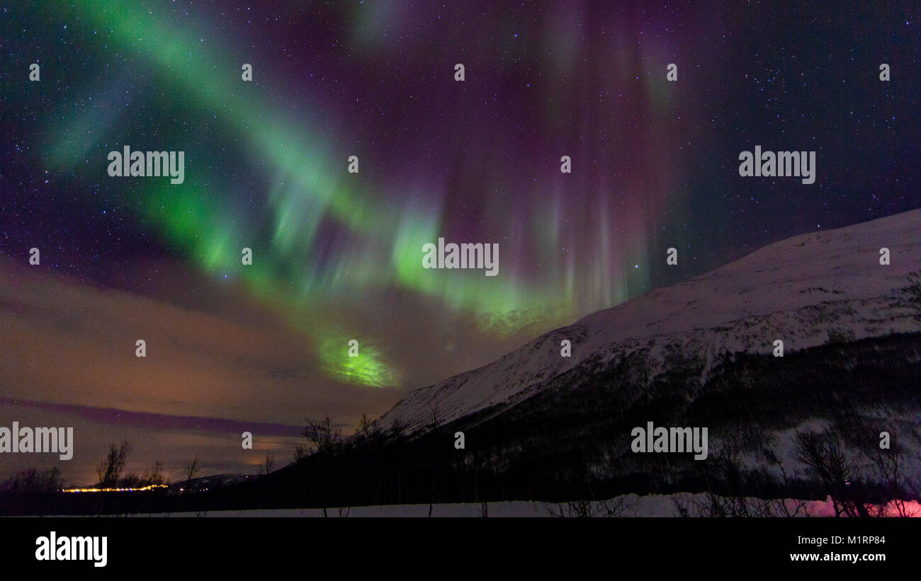 Tromso, Norway. Northern lights display over small town. Stock Photo