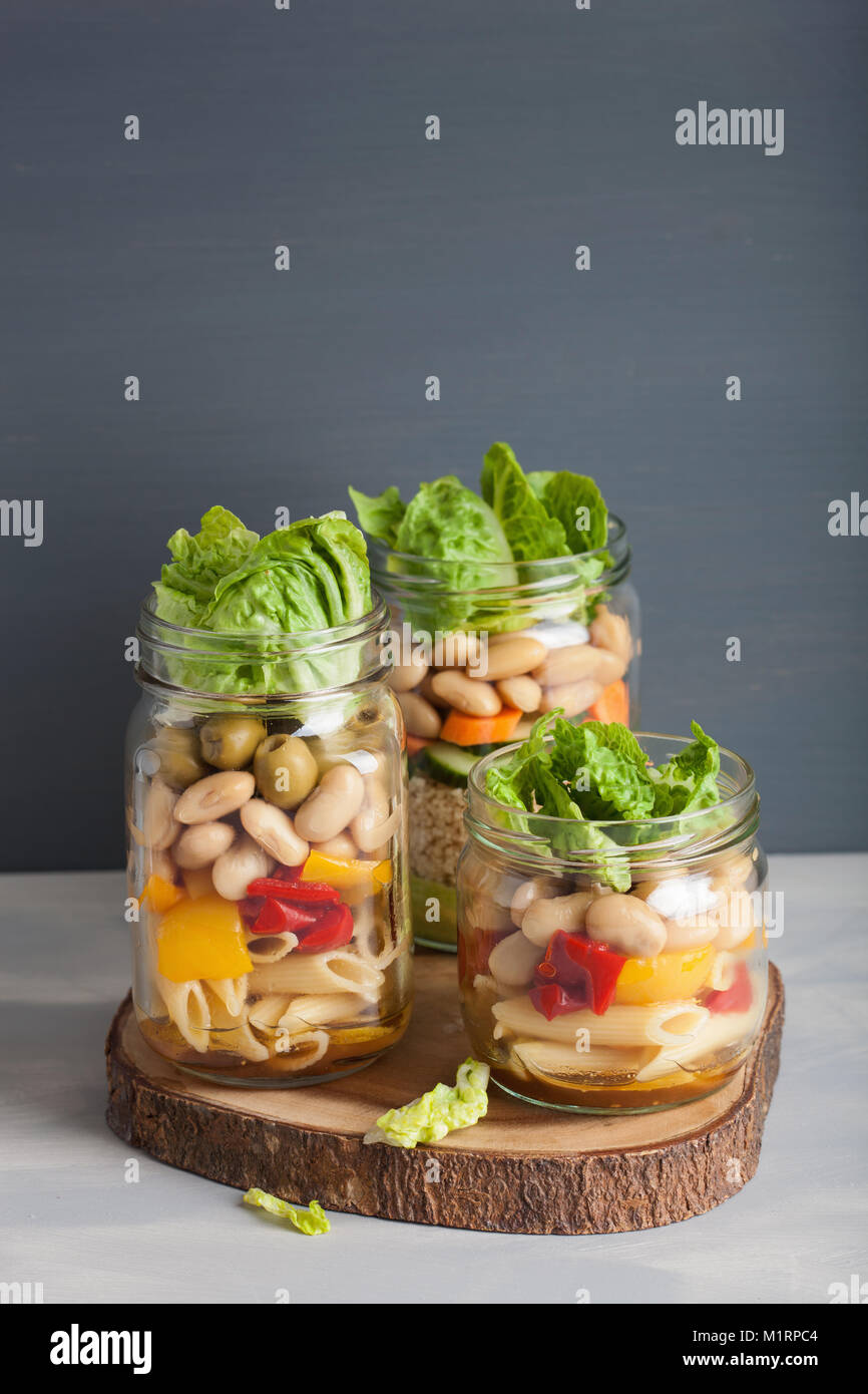 vegan couscous and pasta salad in mason jars with vegetables beans