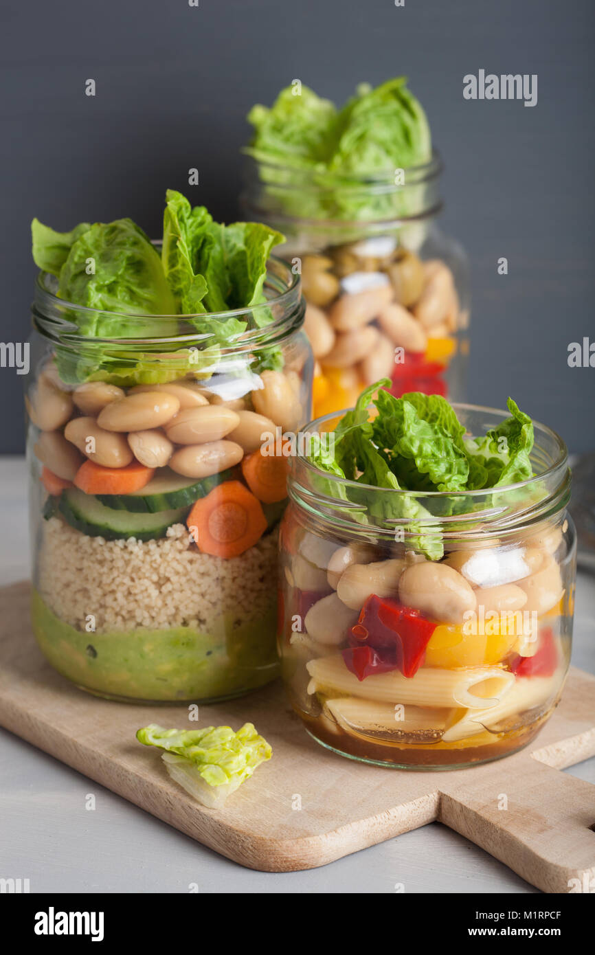 vegan couscous and pasta salad in mason jars with vegetables beans