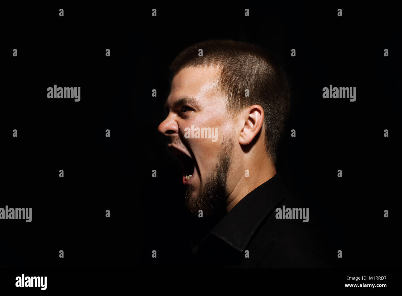 Scared face of spooky man in the dark. The man is yelling Stock Photo