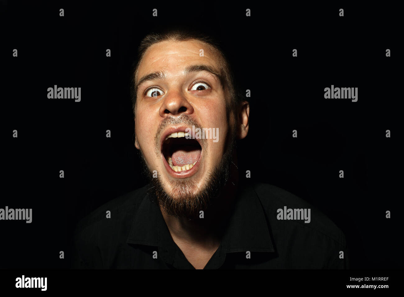 Scared face of spooky man in the dark. The man is yelling Stock Photo