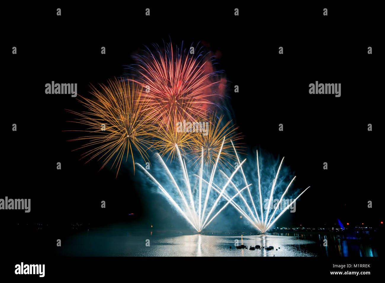Bright and colorful fireworks against a black night sky.Fireworks for new year. Beautiful colorful fireworks display on the urban lake for celebration Stock Photo