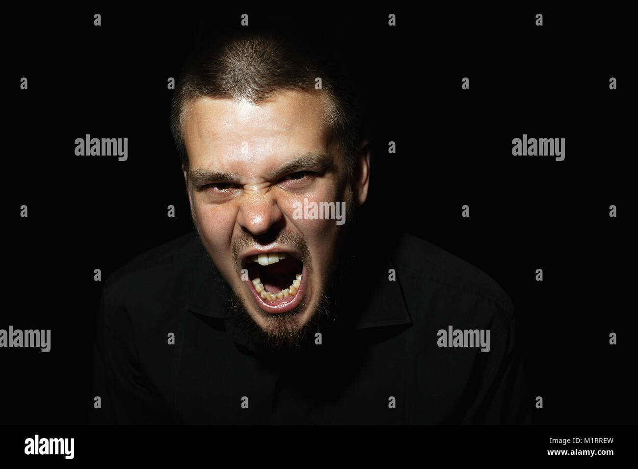 Scared face of spooky man in the dark. The man is yelling Stock Photo