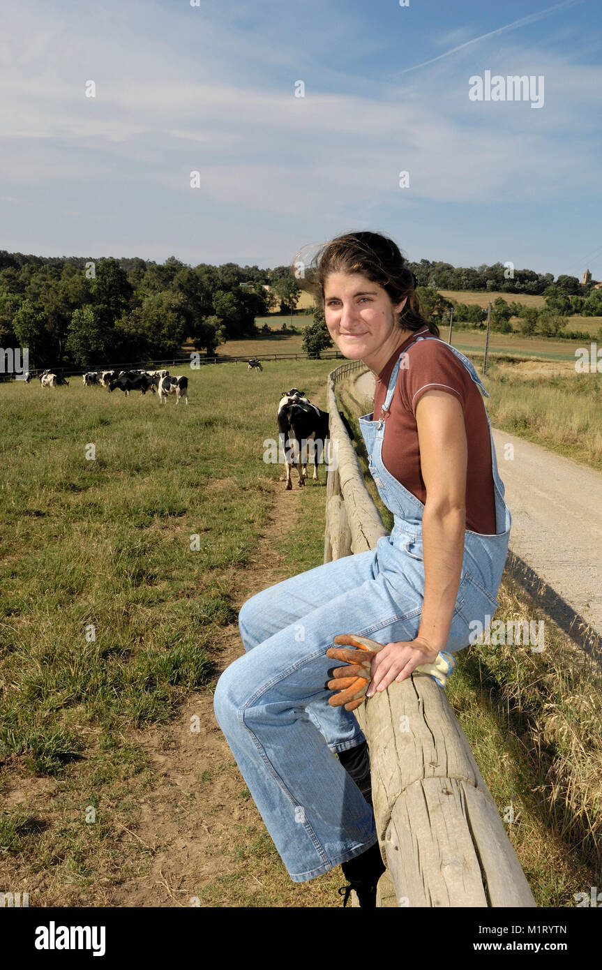 farmer sitting on a fence and behind her herd of cows Stock Photo - Alamy