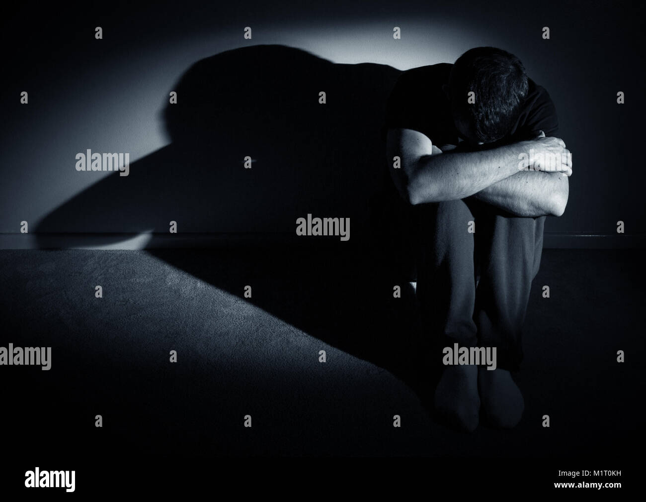 Person looking depressed, sad, alone in harsh light Stock Photo