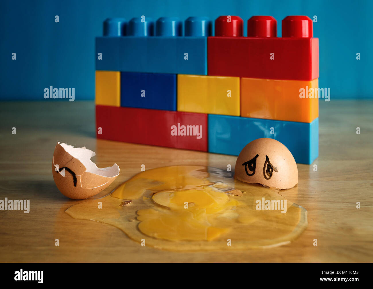 Egg with sad face that has fallen off wall and cracked open Stock Photo