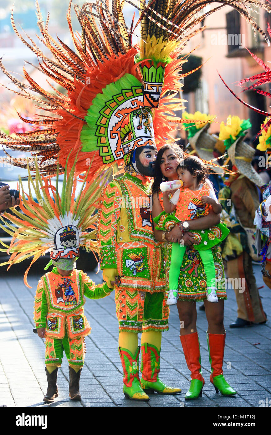 A mexican family dressed with traditional mexican folk costumes during the mexican carnival. Huhue wooden handmade mask, plume. Editorial use only. Stock Photo