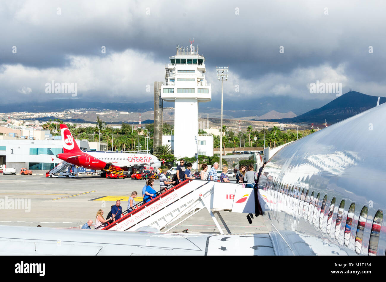 Passengers board a plane at Tenerife-South Airport, Spain, as storm clouds gather above Stock Photo