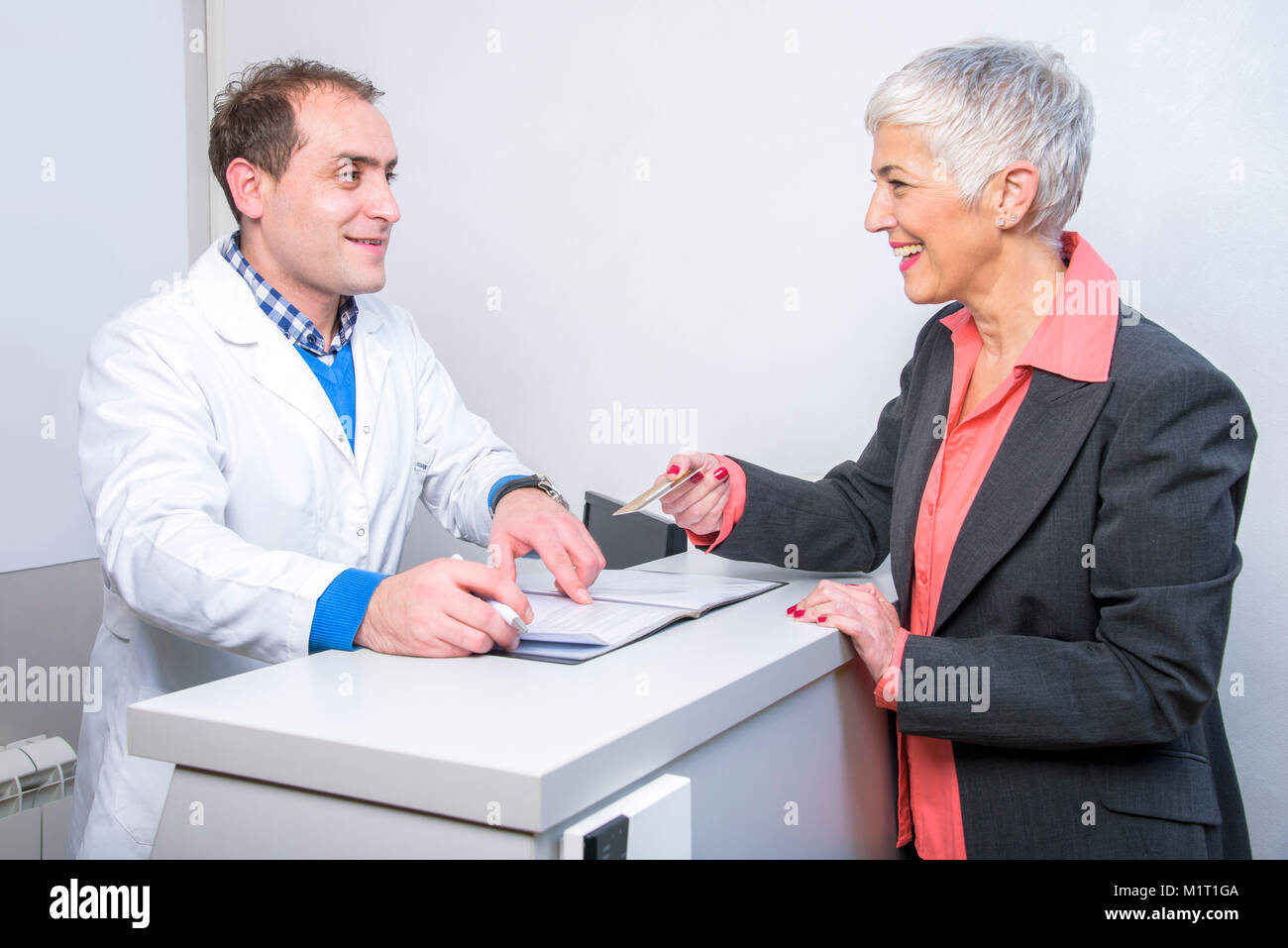 Happy older lady paying her medical bill Stock Photo