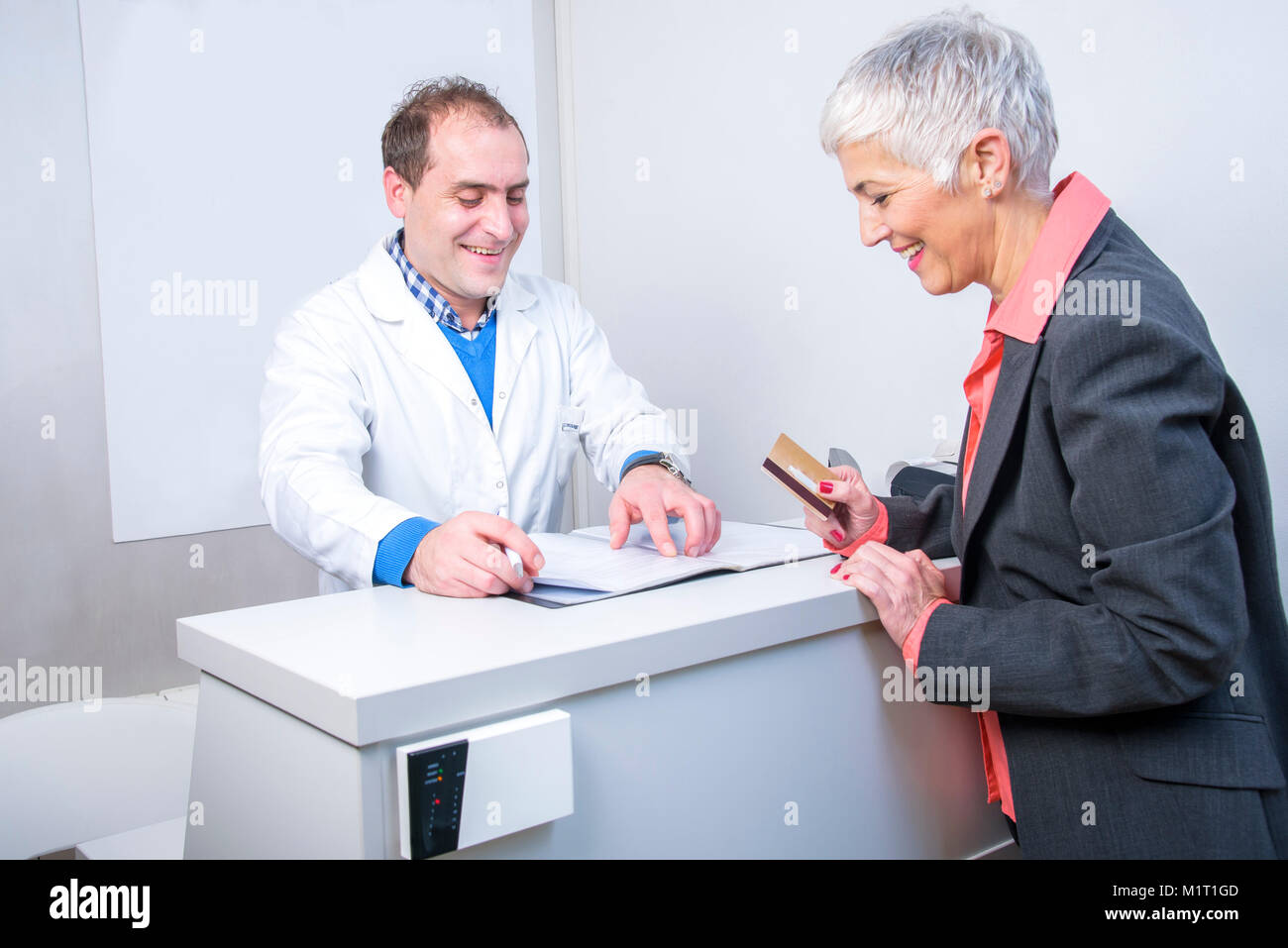 Happy older lady paying her medical bill Stock Photo