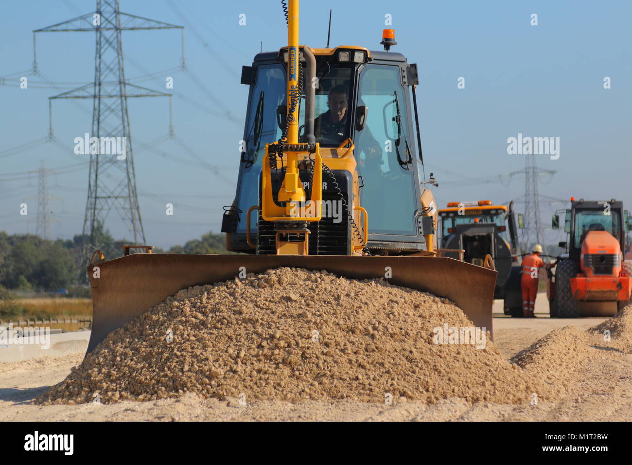 A Komatsu dozer pushes out sub base stone ready to be compacted then rolled before being trimmed for tarmac. Stock Photo