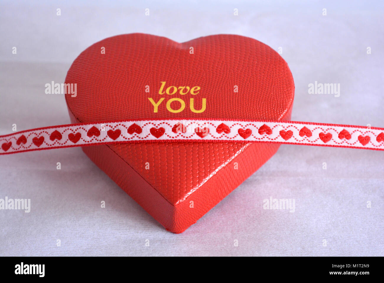 A red heart shaped gift box draped with red hearts ribbon, a romantic ...
