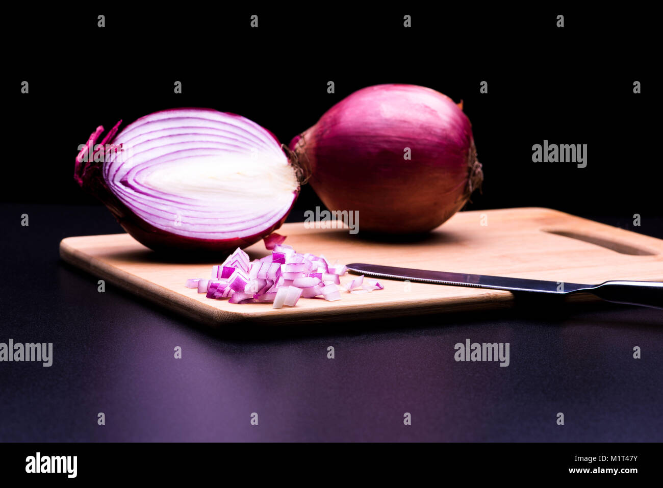 Red onion cut and all in black background Stock Photo - Alamy