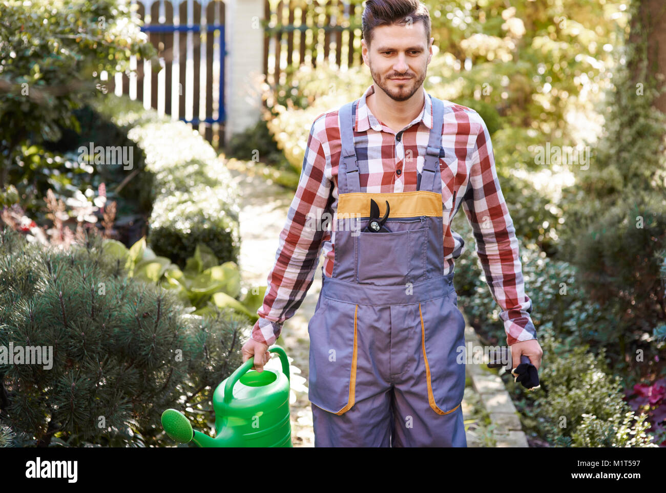 Gardener in uniform holding watering can Stock Photo