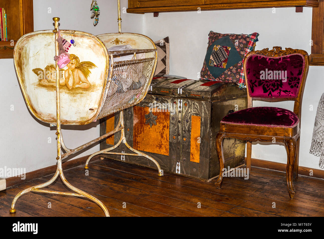 Antique cradle with chest and purple wooden chair in vintage interior Stock Photo