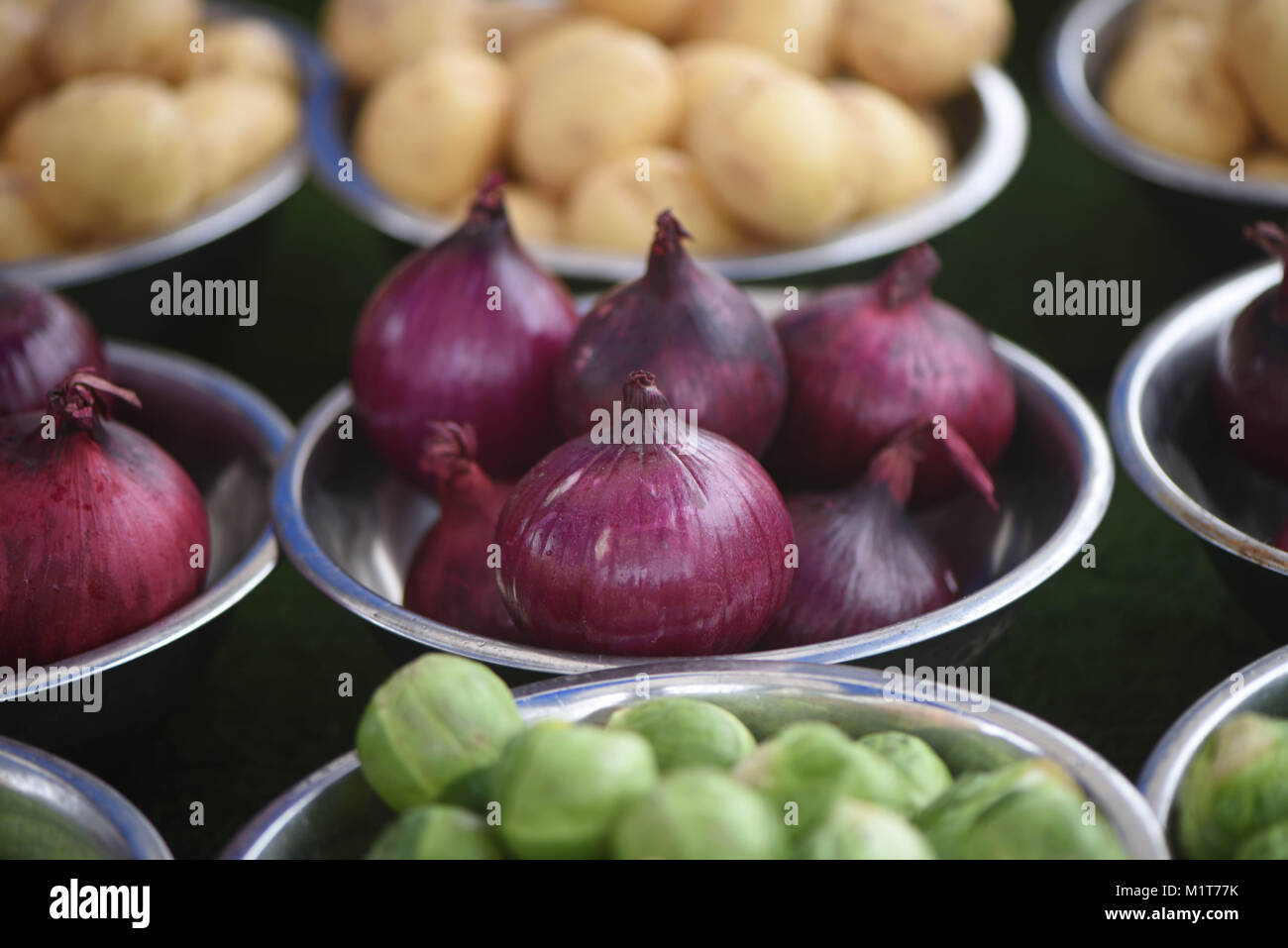 vegetable market stall with bowls of fresh purple color red onions and potatoes in the background Stock Photo