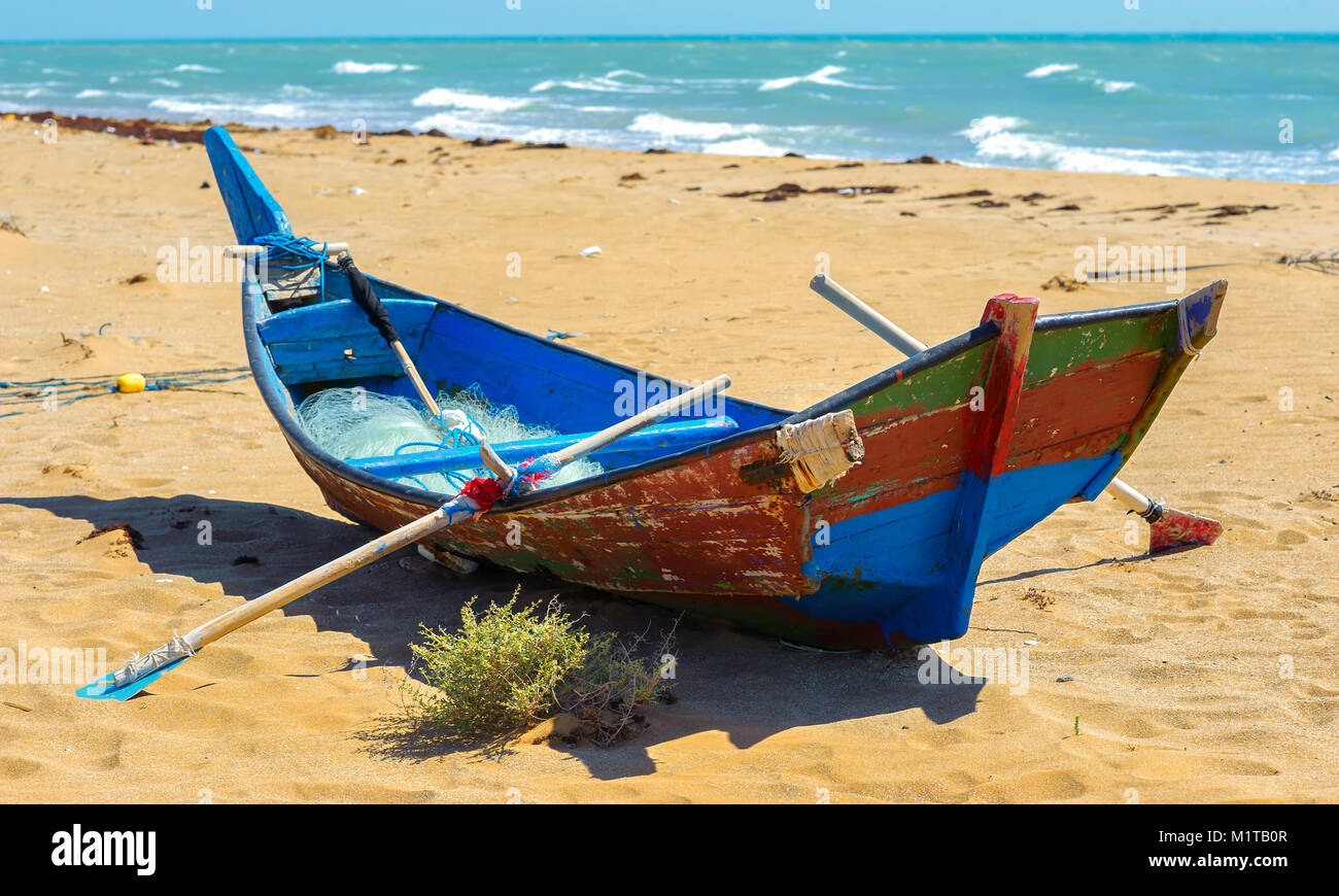 the fishing boat with network and oars costs on the beach of the Persian Gulf Stock Photo