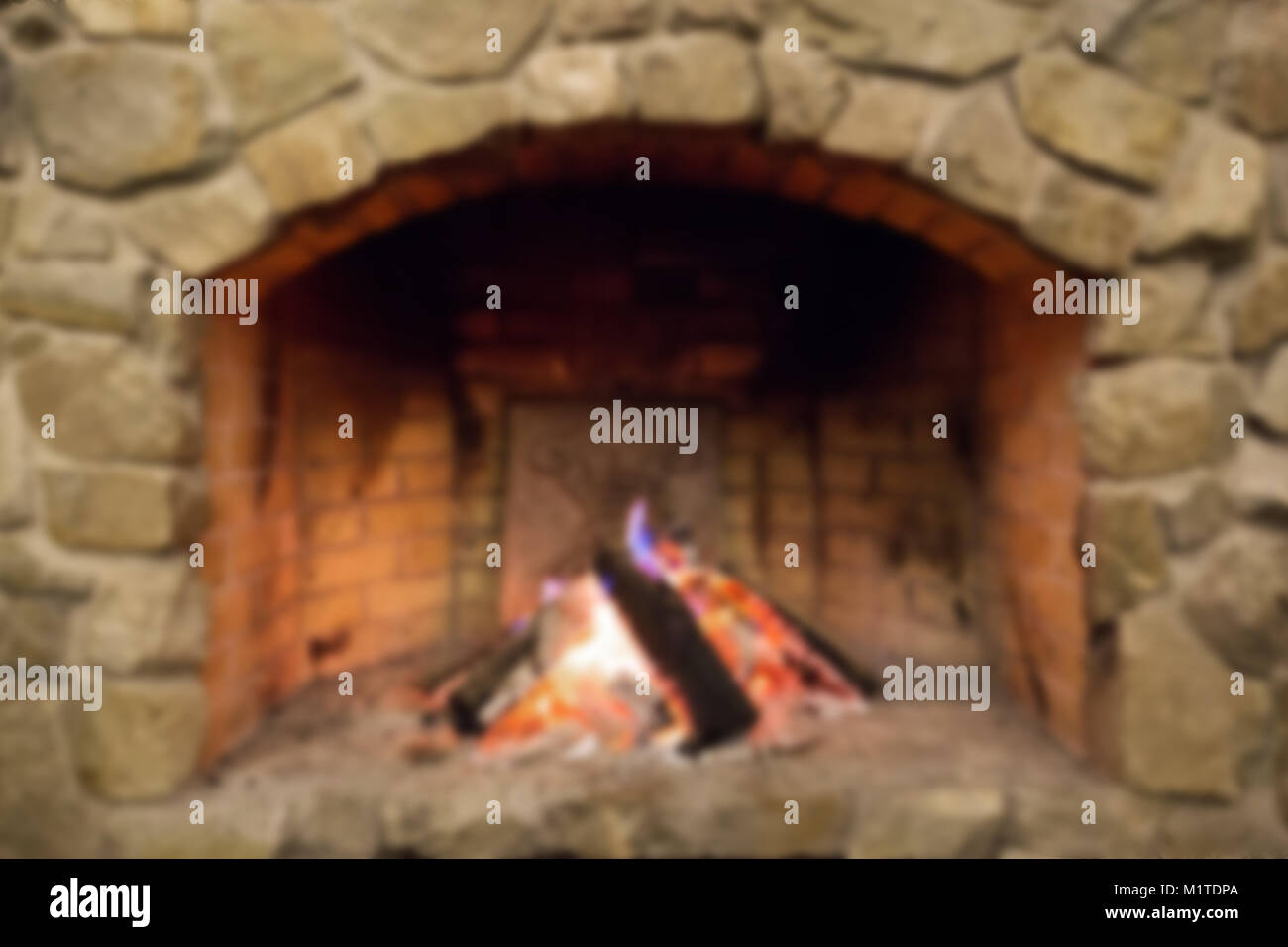 in the wood burning stone fireplace. blurred background Stock Photo - Alamy