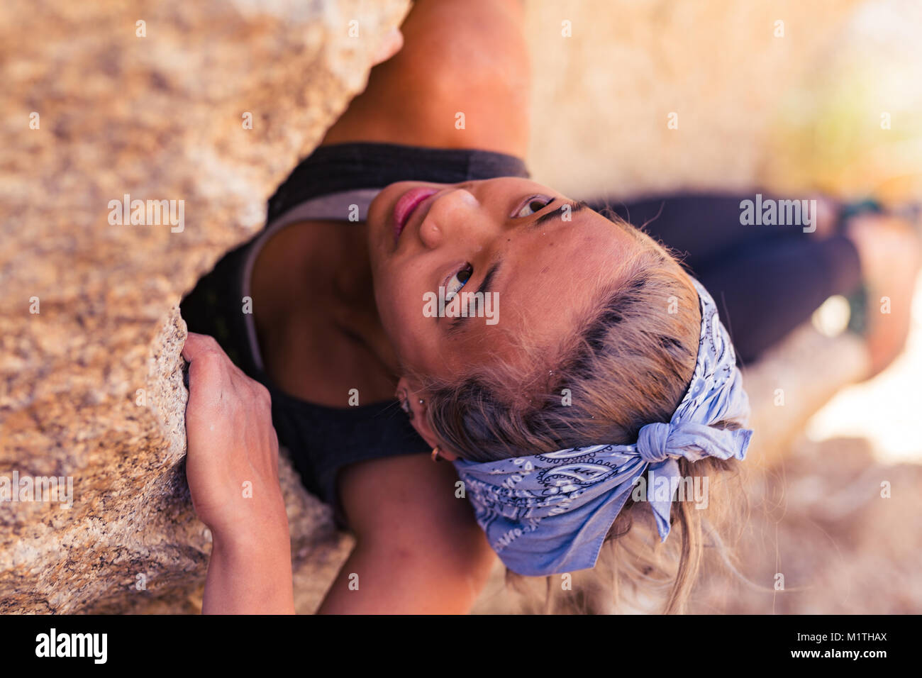Closeup of petite asian woman rock climbing outdoors concentrates on the challenge Stock Photo