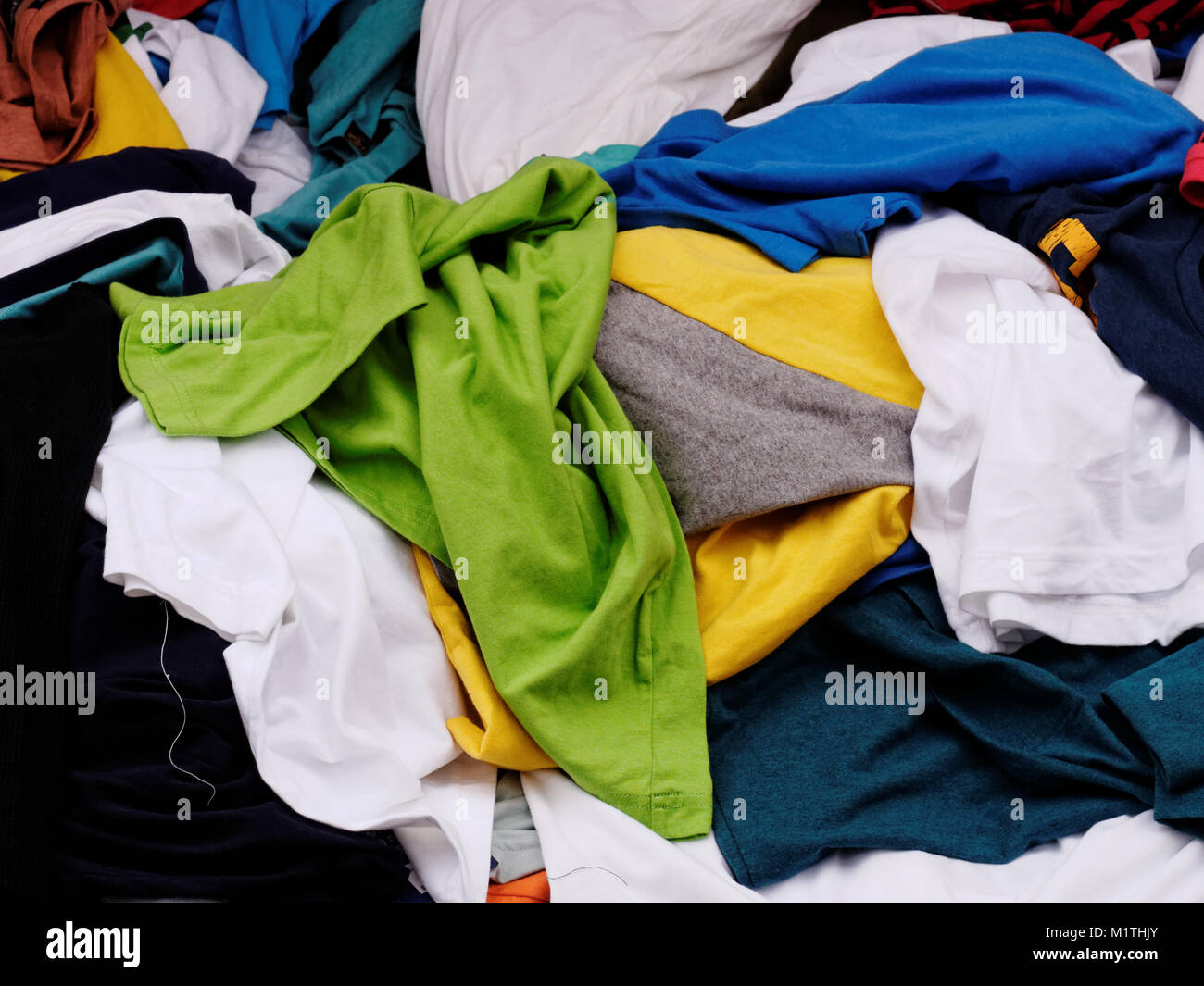 Multi-colored, green,blue, yellow and white, pile of clothes on sale in the apparel shop in the street market Stock Photo