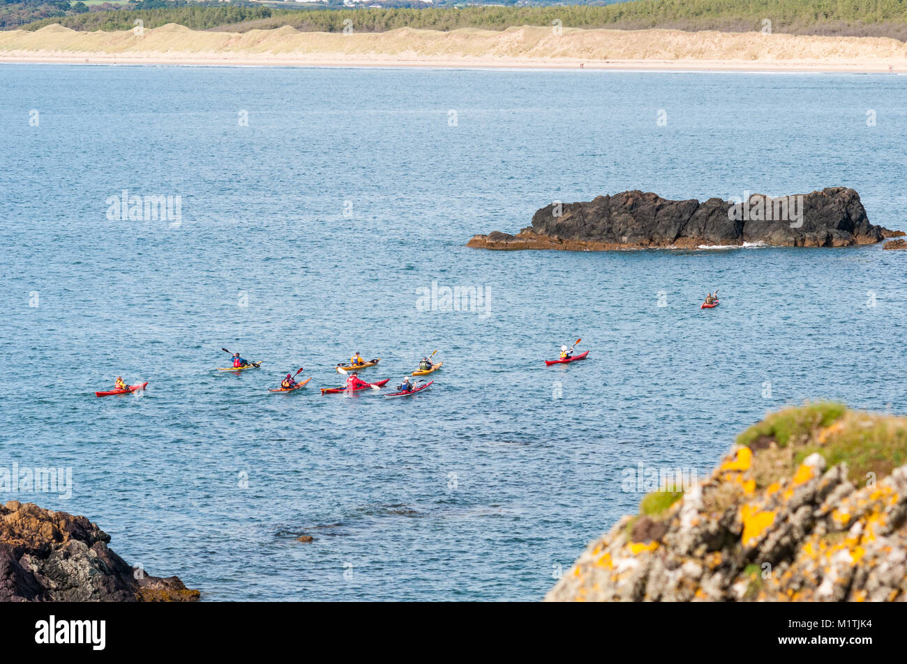 A group of people kayaking off the coast of Llanddwyn island in the Irish sea on a late Summer day, Anglesey, Wales Stock Photo