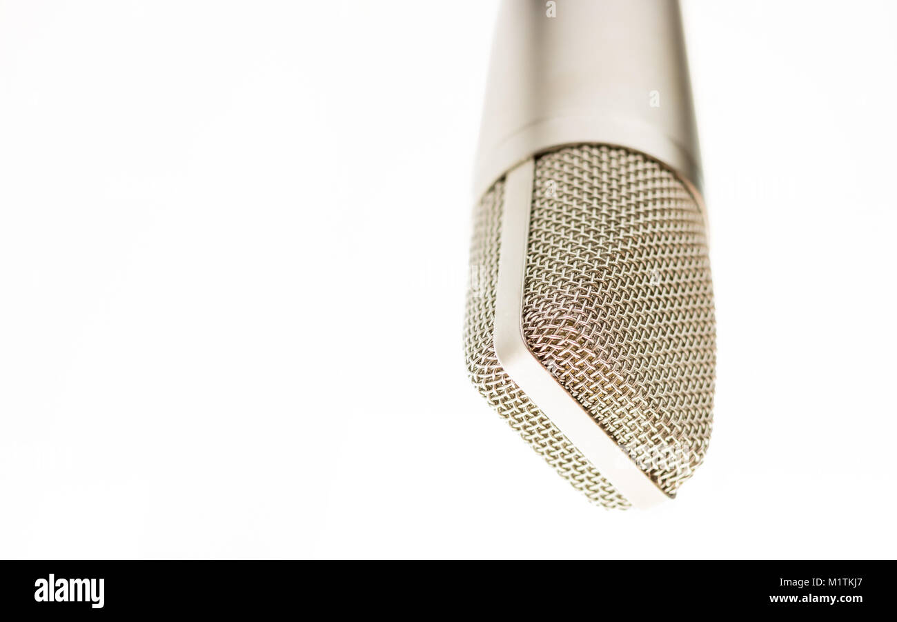 An old fashioned silver microphone is placed on a stand upside down. The background is all white Stock Photo