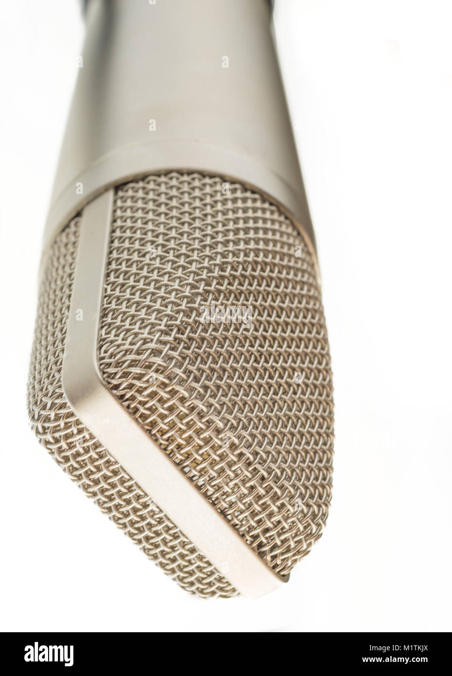 An old fashioned silver microphone is placed on a stand upside down. The background is all white Stock Photo